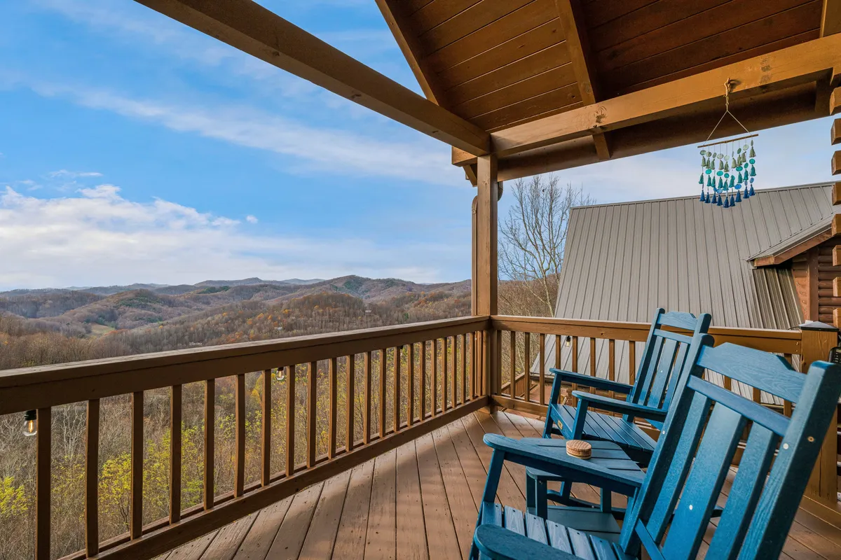 A deck space with classic rocking chairs and wind chimes, all overlooking stunning mountain views. The scene suggests quiet mornings, soothing breezes, and a direct connection to the natural surroundings.